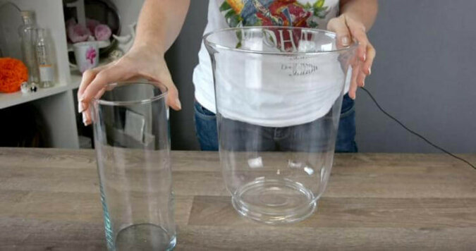Kobieta wkłada świeczkę do szklanego wazonu i wszystko napełnia wodą